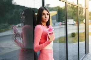 bellissimo giovane sportivo donna potabile acqua dopo in esecuzione. in forma jogger ragazza assunzione un' rompere dopo sport. stile di vita, le persone, sport e tempo libero concetto. foto