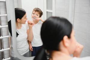 sorridente madre e ragazzo figlio spazzolatura denti nel bagno foto