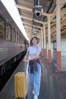 giovane donna con valigia aspetta a il la metropolitana stazione mentre il treno arriva, turismo e viaggio nel il estate. vacanze per il alunno. opera e viaggio foto