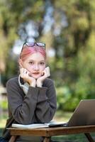 donna Lavorando a il il computer portatile nel il Giardino dietro la casa con un' lotto di verde, il computer portatile e ritratto di donna nel parco per formazione scolastica foto