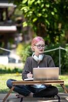 donna Lavorando a il il computer portatile nel il Giardino dietro la casa con un' lotto di verde, il computer portatile e ritratto di donna nel parco per formazione scolastica foto