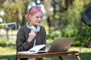 donna Lavorando a il il computer portatile nel il Giardino dietro la casa con un' lotto di verde, il computer portatile e ritratto di donna nel parco per formazione scolastica foto