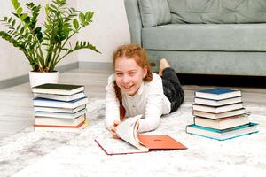 ridendo ragazza a casa su il pavimento circondato di libri foto