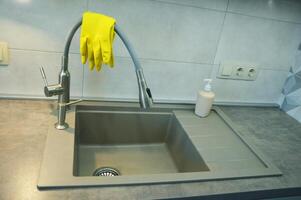 cucina Lavello con flessibile rubinetto senza piatti. Là siamo giallo pulizia guanti su il rubinetto. foto