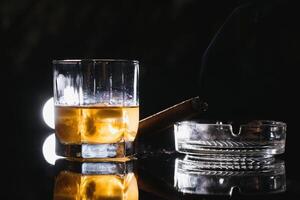 bicchiere di whisky con ghiaccio cubi e fumo sigaro su tavolo foto