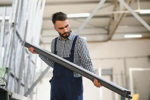 lavoratore le misure e prepara pvc profili nel il laboratorio per finestra e porta produzione foto