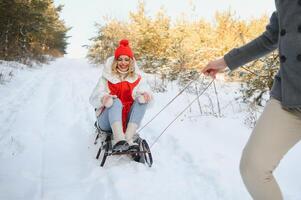 bellissimo giovane coppia nel amore avendo divertimento su un' inverno vacanza nel montagne, fidanzato spingendo fidanzata su un' slitta, godendo nevoso, nebbioso inverno giorno all'aperto foto