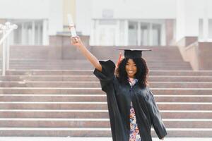 studente laureato afroamericano allegro con il diploma in sua mano foto