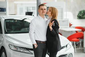 giovane bellissimo contento coppia acquisto un' macchina. marito acquisto auto per il suo moglie nel un' salone. auto shopping concetto foto