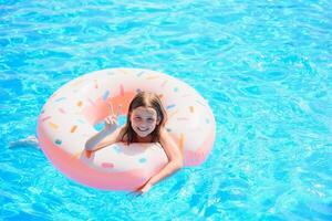 contento poco ragazza giocando con colorato gonfiabile squillare nel all'aperto nuoto piscina su caldo estate giorno. bambini imparare per nuotare. bambino acqua giocattoli. bambini giocare nel tropicale ricorrere. famiglia spiaggia vacanza. foto