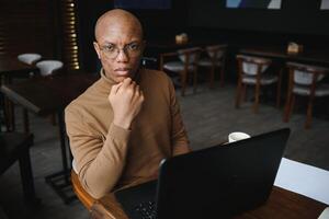 africano americano attività commerciale uomo con il computer portatile nel un' bar. foto