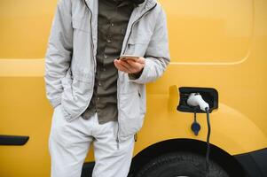 elegante uomo inserti il ricarica cavo in il presa di corrente di elettrico auto foto