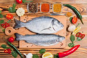 crudo pesce cucinando e ingredienti. dorado, Limone, erbe aromatiche e spezie. superiore Visualizza con copia spazio su tavolo foto