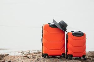 colore viaggio valigia su sabbioso spiaggia con turchese mare sfondo, estate vacanze concetto foto