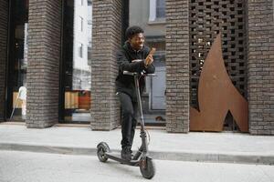 attivo tempo libero concetto. lato Visualizza di nero maschio alunno guida in piedi scooter al di sopra di mattone strada, copia spazio per anno Domini o testo foto