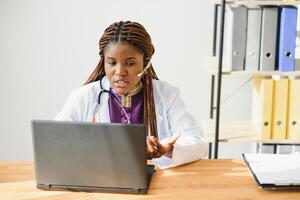 africano femmina medico consulenza paziente rendere in linea webcam video chiamata su il computer portatile. nero donna terapista videoconferenza nel a distanza computer assistenza sanitaria telemedicina virtuale Chiacchierare. telemedicina video chiamata foto