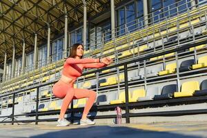 donna fitness facendo sit up nello stadio lavorando. ragazza sportiva che esercita addominali, all'aperto foto