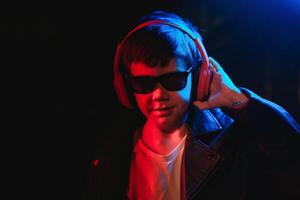 adolescente ragazzo ascoltando per musica con cuffia, neon leggero trend ritratto. sembra a il telecamera foto