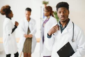 ritratto di un' africano medico nel davanti di il suo medico squadra. foto