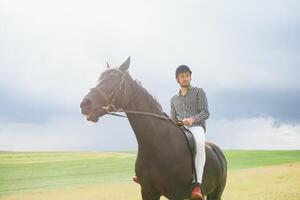 bellissimo uomo equitazione un' cavallo su campo a estate foto