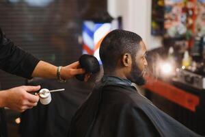 africano maschio cliente ottenere taglio di capelli a barbiere negozio a partire dal professionale parrucchiere. foto