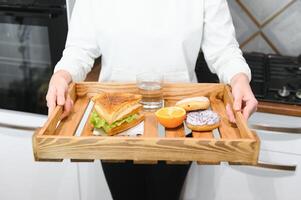 giovane donna Tenere vassoio con prima colazione cibo a casa foto