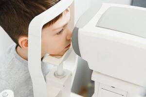 optometria concetto. femmina optometrista ottico medico esamina vista di bambino ragazzo nel occhio oftalmologico clinica. foto