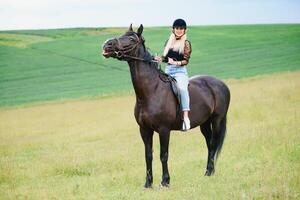 bellissimo ragazza equitazione un' cavallo nel campagna. foto