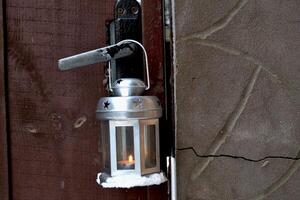 candela lanterna sospeso su il porta maniglia all'aperto nel inverno. freddo stagione. hygge stile. foto