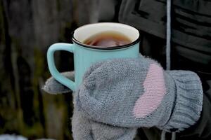 un' boccale di tè nel freddo tempo atmosferico. un' tazza di tè nel donna di mani. foto