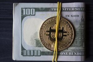 d'oro bitcoin e dollari nel maschio mano su un' buio blu di legno sfondo. oro moneta di criptovaluta. foto