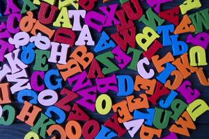 multicolore lettere su un' buio blu di legno sfondo. colorato di legno alfabeto su un' tavolo. foto