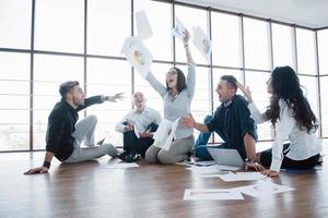 strategia di successo insieme. colleghi di lavoro allegri che lanciano carte in ufficio creativo. cooperazione aziendale successo. disegno di pianificazione disegnare. concetto di lavoro di squadra foto