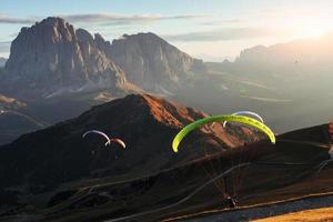 spettacolo mozzafiato. molti dei parapendii che sorvolano le montagne dolomitiche del seceda la sera all'alba foto