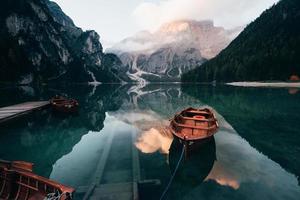 aspettando i visitatori. barche di legno sul lago di cristallo con maestosa montagna alle spalle. riflesso nell'acqua foto