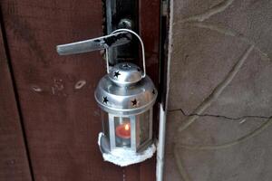candela lanterna sospeso su il porta maniglia all'aperto nel inverno. freddo stagione. hygge stile. foto