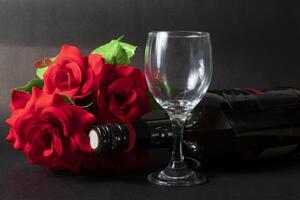 rosso rosa e vino bottiglia con vuoto vino bicchiere su nero sfondo. San Valentino giorno concetto foto