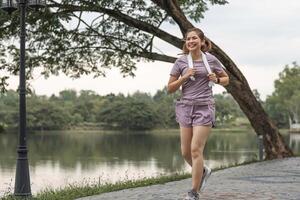 giovane bellissimo asiatico donna jogging a il parco nel il mattina, Salute e esercizio concetto. foto