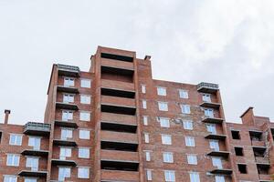 il mattone Casa è multipiano, il costruzione di un' rosso mattone Casa, il vetri di balconi, il finestre nel il Casa, il edificio è un' linea. foto