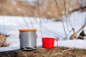 alluminio leggero pentola per cucinando nel natura, campeggio utensili, un' metallo padella, un' rosso tazza, quello dello scalatore attrezzatura oggetti. foto