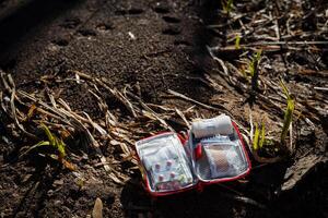 primo aiuto kit nel difficile escursioni a piedi situazioni. medicinali per un' turista, un' Borsa con pillole bugie su il terra, un Aperto primo soccorso kit aiuta un' persona perso nel il foresta. foto