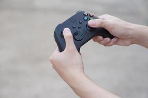 vicino su mani hold nero joystick o gioco controllore consolle. concetto, tecnologia dispositivo per divertimento di in linea a distanza video Giochi per computer schermo. hobby, tempo libero e ricreazione attività. foto