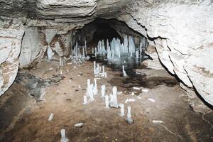 un' grotta metropolitana ghiaccio stalagmiti crescere su il pavimento, un' tunnel nel il carsico cavità di il montagna, un' calcare grotta nel inverno. foto