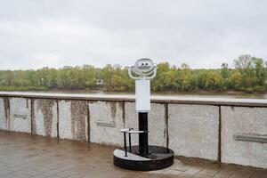 panoramico binocolo In piedi su il osservazione ponte, il città telescopio, il argine nel il parco, il dispositivo per Guarda in il distanza, il telescopio, per vedere il paesaggio, per prendere in considerazione il orizzonte foto