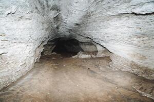 un' lungo tunnel metropolitana. grotta carsico, speleo escursione per il grotta, calcare depositi, acqua lavaggi lontano il roccia nel il roccia. foto