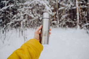 hold un' grigio thermos con tè nel il tuo mano. metallo thermos di argento colore. fatto di acciaio. foto