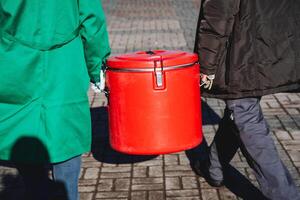 persone trasportare un' plastica ermetico contenitore, un' rosso vuoto cibo contenitore, un' cibo servizio, pericoloso carico, e cibo consegna. foto