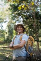 giovane uomo asiatico il trekking tra alberi con zaino, giovane uomo godere solo nel foresta. campeggio, escursionismo, in viaggio, ricerca per avventura concetto foto