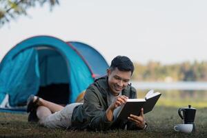 uomo leggere libro mentre viaggiatore con campeggio. concetto di moderno persone stile di vita nel Lavorando foto