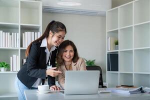 Due donna d'affari discutere compagno discutere progetto su il computer portatile nel ufficio. Due collega di professionale attività commerciale persone Lavorando insieme a spazio di lavoro foto
